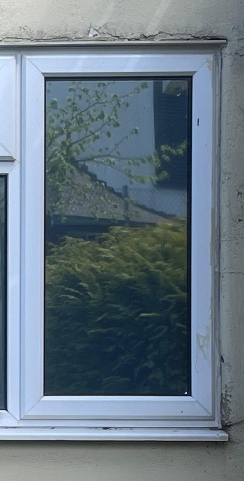 Solar tinted rear window with a reflective finish, viewed from outside